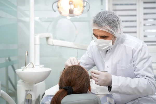 Estomatólogo tratando los dientes del cliente en la clínica . — Foto de Stock