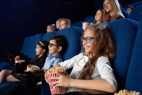 Gyerekek néz filmet a moziban, gazdaság Popcorn vödör. — Stock Fotó