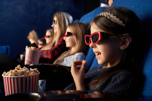 Bambina mangiare popcorn, guardare cartone animato nel cinema . — Foto Stock