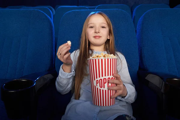 Όμορφο κορίτσι τρώει ποπ κορν, βλέποντας φιλμ στον κινηματογράφο. — Φωτογραφία Αρχείου