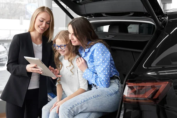Negociante de carro mulher de consultoria com a filha no salão de auto — Fotografia de Stock