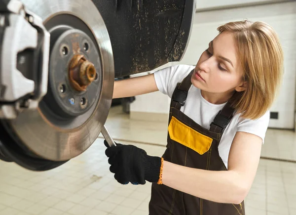Mecánica femenina enfocada cambiando neumático de auto en taller — Foto de Stock