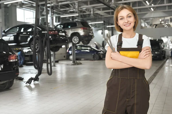 Junge positive Frau im Overall, die im Autoservice arbeitet — Stockfoto