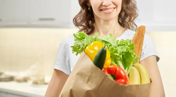 Frau hält Papiertüte mit Lebensmitteln in Küche — Stockfoto