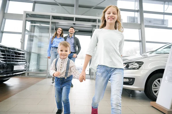 Funny boy with elder sister entering in big auto showroom — Stock Image Funny boy with elder sister entering in big auto showroom Royalty Free Stock Photos