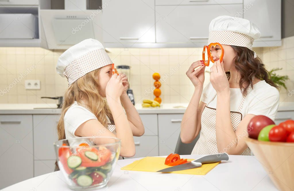 Side view of funny mother and daughter in cooking hats
