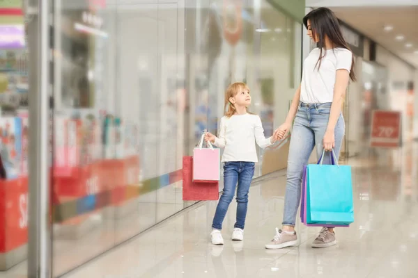 女の子とショッピング モールの店の窓の近くに立って母. — ストック写真