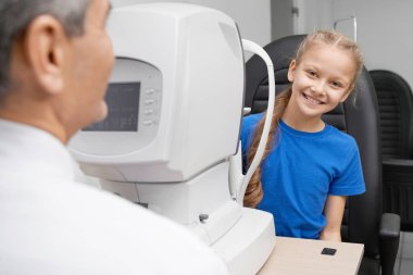 Kız kamera bakıyor ve vizyon kontrol ederken gülüyor