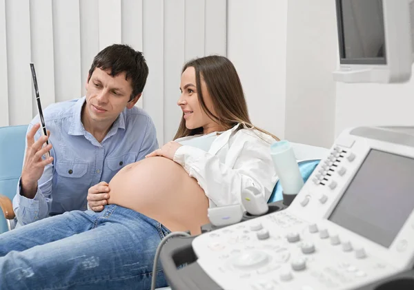 Radostní budoucí rodiče se dívají na Ultrazvukový obraz dítěte — Stock fotografie