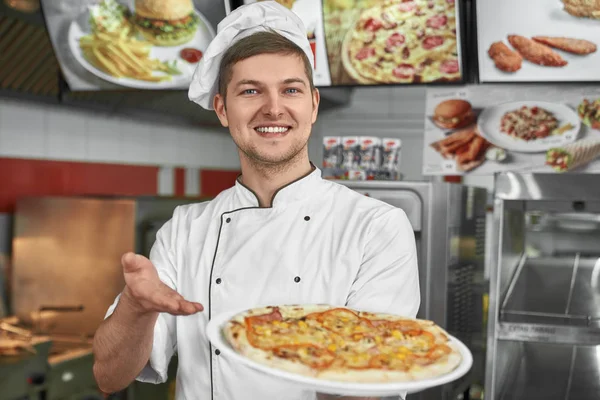 Férfi szakács, fehér egységes kínál ízletes pizzát az ügyfeleknek — Stock Fotó