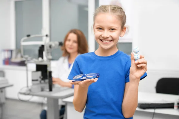 Vista frontale della ragazza che tiene gli occhiali e la lente nel negozio ottico — Foto Stock