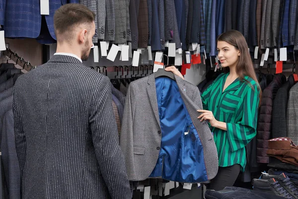 Consultor de loja escolher e mostrar jaqueta para o cliente . — Fotografia de Stock