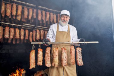 Duman evinde poz veren tütsülenmiş et ve kasap parçaları.