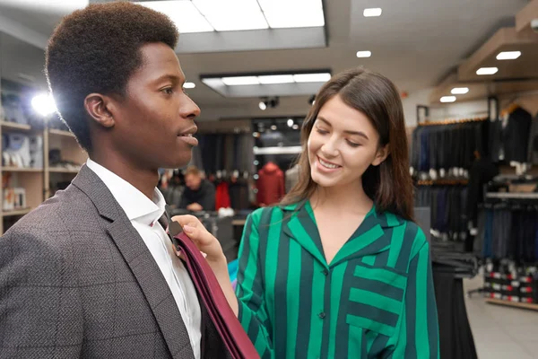 Homem na boutique escolhendo gravata, sorrindo assistente ajudando . — Fotografia de Stock