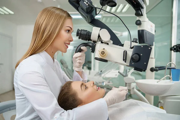 Вид сбоку на опытного стоматолога, смотрящего в микроскоп — стоковое фото