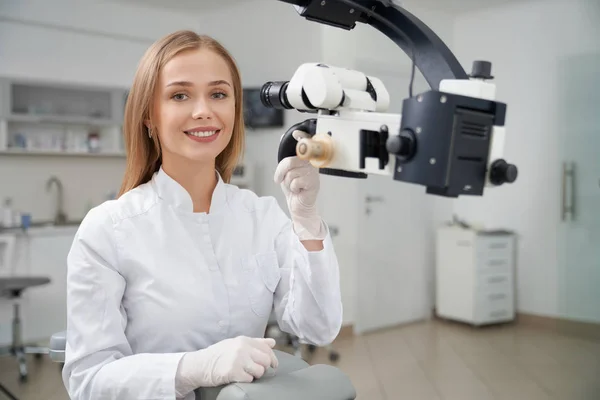 Stomatologo in posa in odontoiatria vicino al microscopio dentale . — Foto Stock