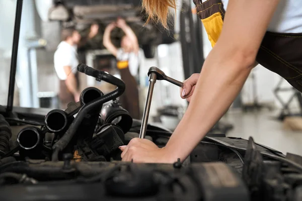 Ženy ruce opravy auta pod kapotou s nářadím. — Stock fotografie