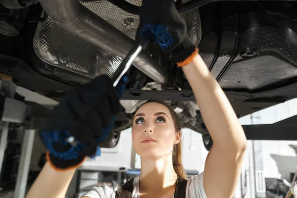 Young woman fixing undercarriage with wrench. — 스톡 사진