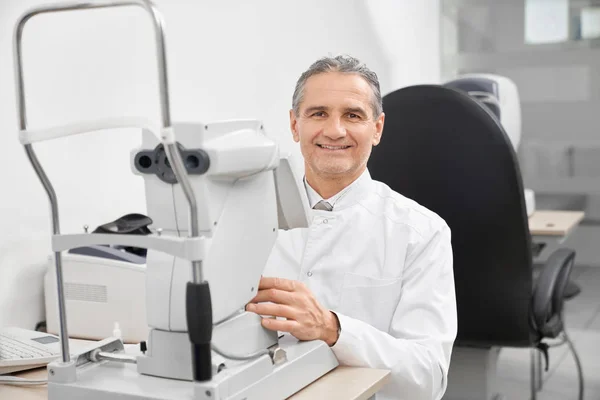 Doctor sonriendo, posando con la moderna máquina de prueba ocular . —  Fotos de Stock