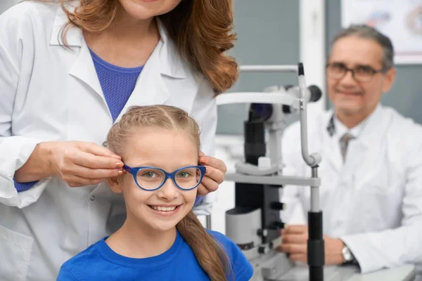 Trabajador médico elegir gafas para chica adolescente bonita . —  Fotos de Stock