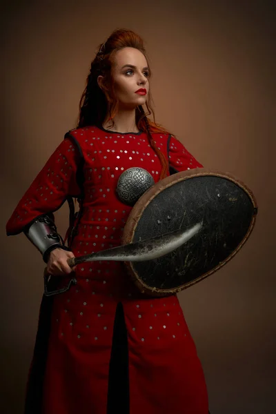 Mujer valiente en túnica medieval posando con arma . — Foto de Stock