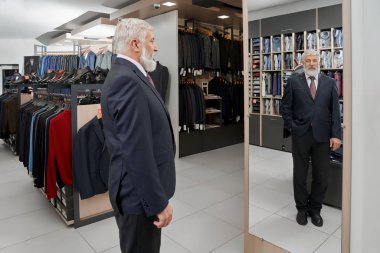 Yaşlı adam resmi akıllı takım butik ayna bakıyor
