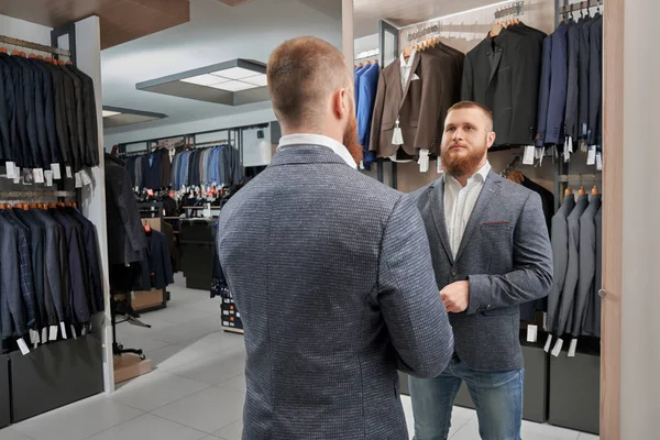 Homem confiante em pé na loja de roupas e escolher roupa — Fotografia de Stock