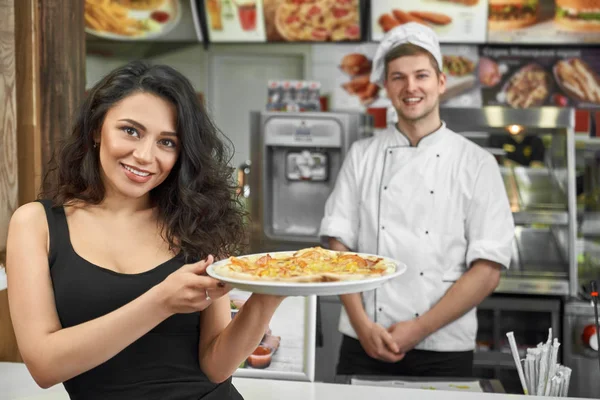 Cliente feliz manteniendo la pizza en las manos y posando en la cafetería — Foto de Stock