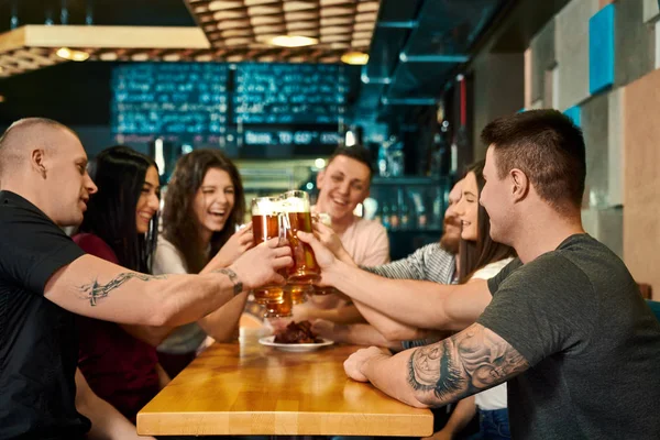 Young friends keeping pints with beer and toasting in pub — 스톡 사진