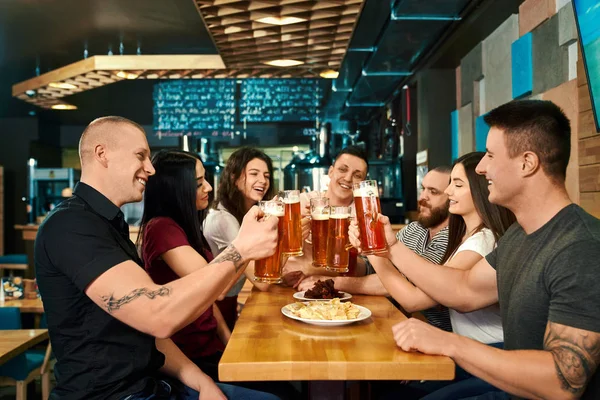 Εταιρεία κάθεται στο μεγάλο τραπέζι και απολαμβάνοντας μπύρα στην παμπ — Φωτογραφία Αρχείου