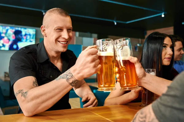 Feliz hombre tostando con cerveza con un amigo en el pub —  Fotos de Stock