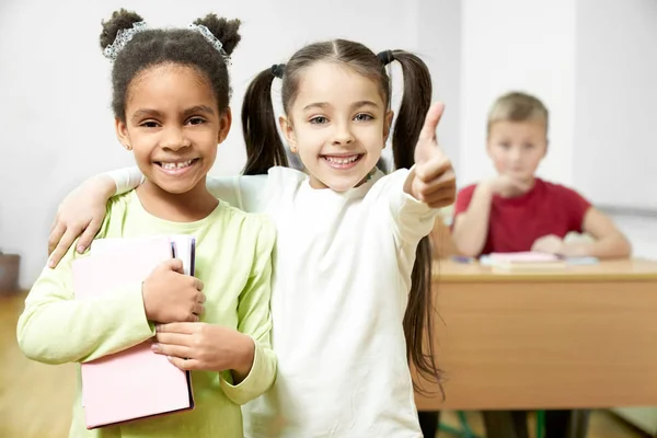 Felices compañeros de clase de pie, mostrando los pulgares arriba . — Foto de Stock