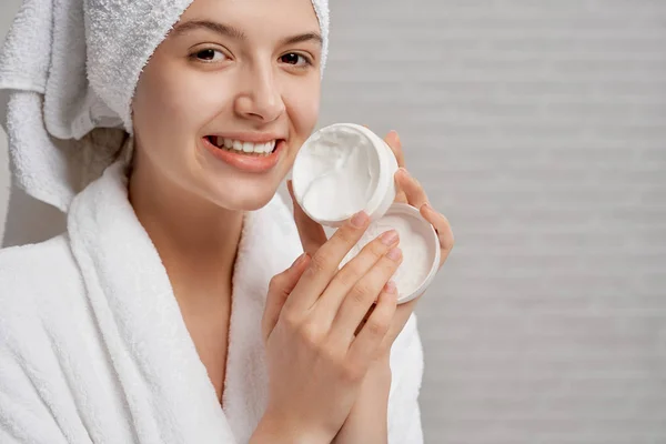 洗顔クリームと白い箱を示すバスローブの女性. — ストック写真