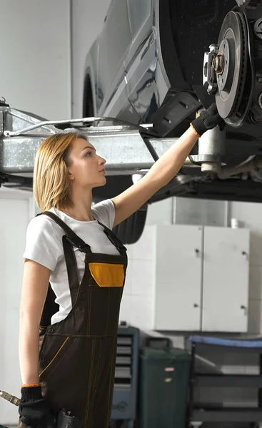 Woman looking at tire of car in auto service — 스톡 사진