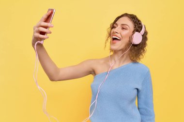 Kulaklıkla müzik dinleyen, gülümseyen kız.