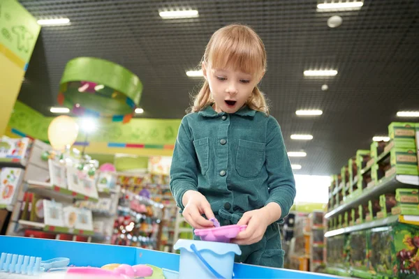 Fille avec bouche ouverte jouant avec la plasticine dans le magasin de jouets — Photo