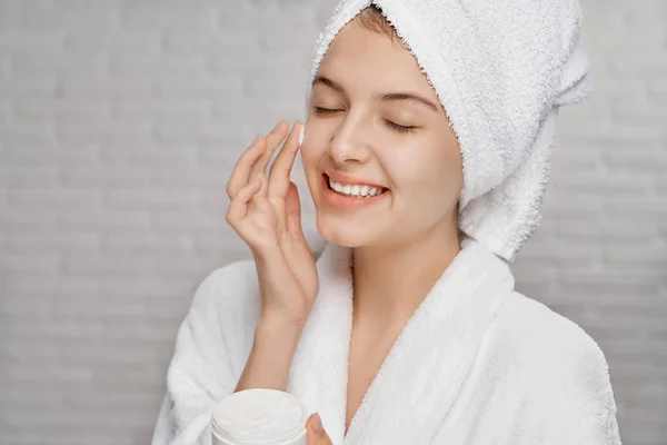 La mujer joven que aplica sobre la crema facial para la hidratación de la piel . —  Fotos de Stock