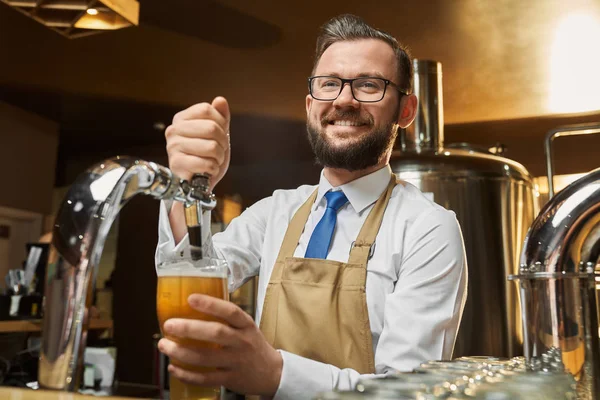 Pozytywny barman nalewanie piwa lager w szkle. — Zdjęcie stockowe