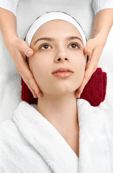 Vrouwelijke handen massage van jonge vrouw gezicht. — Stockfoto