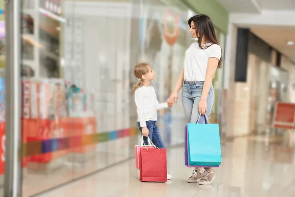 Mãe olhando para a menina bonito enquanto em pé no grande shopping — Fotografia de Stock