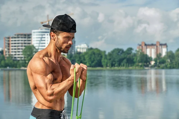 Hombre atlético haciendo ejercicios con expansor y tirando . — Foto de Stock