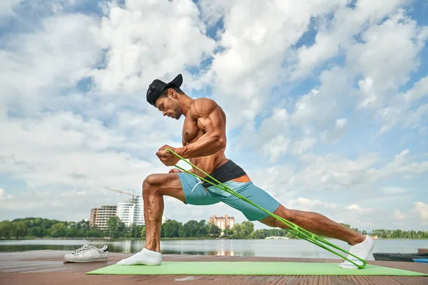 Hombre haciendo ejercicios de embestida para las piernas con expansor . — Foto de Stock