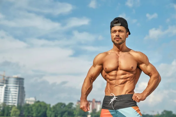 Snygg och sexig manlig bodybuilder poserar utomhus. — Stockfoto