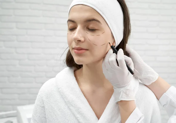 Vrouw een bezoek aan chirurg en het doen van tillen op gezicht in kliniek — Stockfoto