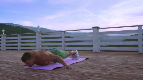 Bonito homem ativo fazendo exercícios push-ups ao ar livre — Vídeo de Stock
