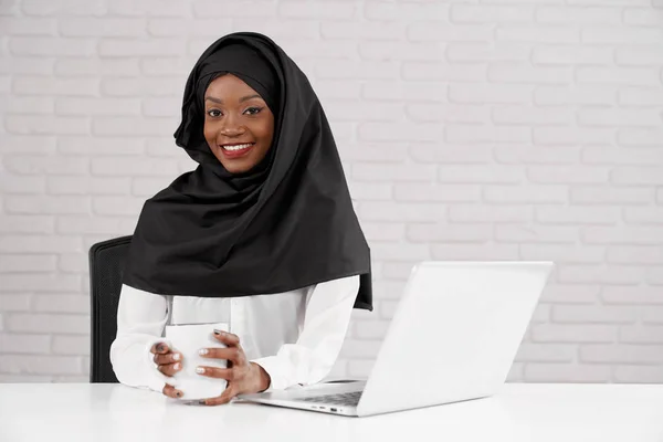 Afrikanische muslimische Geschäftsfrau posiert im Büro, am Arbeitsplatz. — Stockfoto