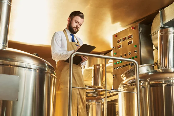 Ingeniero serio inspeccionando el proceso de la cervecería . — Foto de Stock