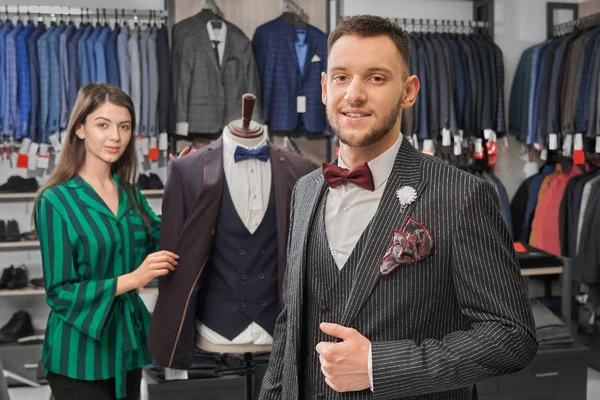 Young, stylish man in elegant suit posing in shop.