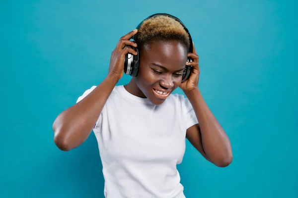 Positive african woman listening music with headphones.