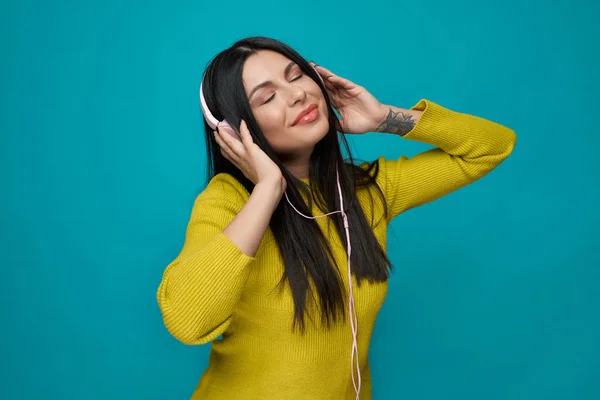 Mujer escuchando música en auriculares con los ojos cerrados . — Foto de Stock